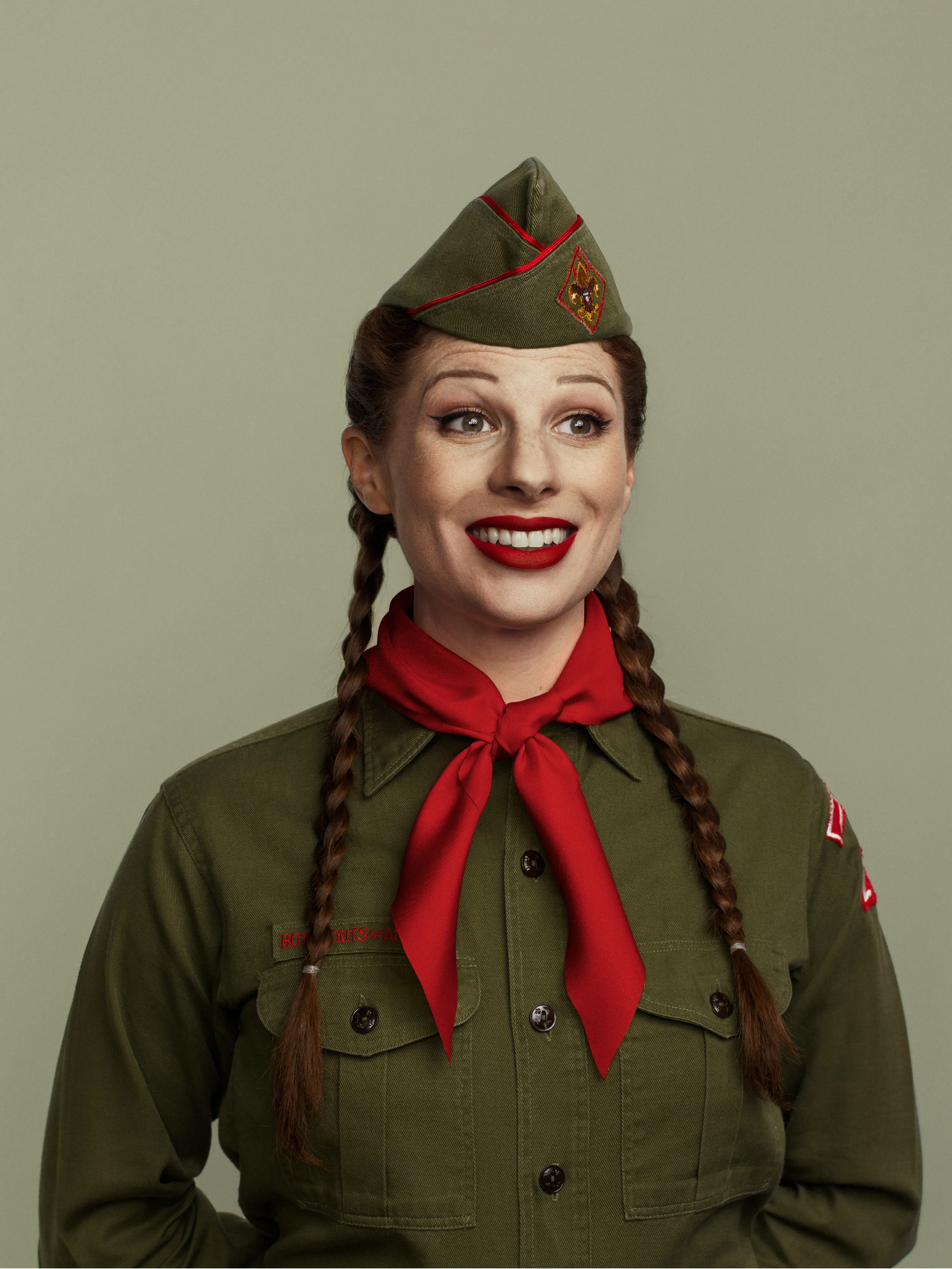 Woman in scout attire smiling in front of seamless background